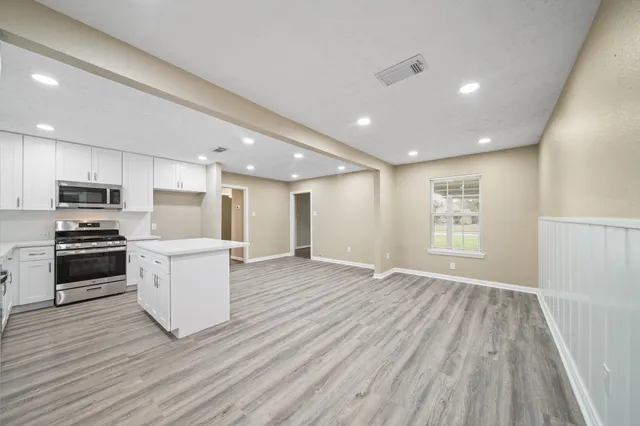 a view of kitchen with cabinets stainless steel appliances and wooden floor