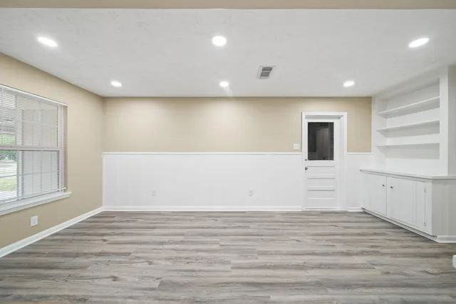 a view of an empty room with wooden floor and windows