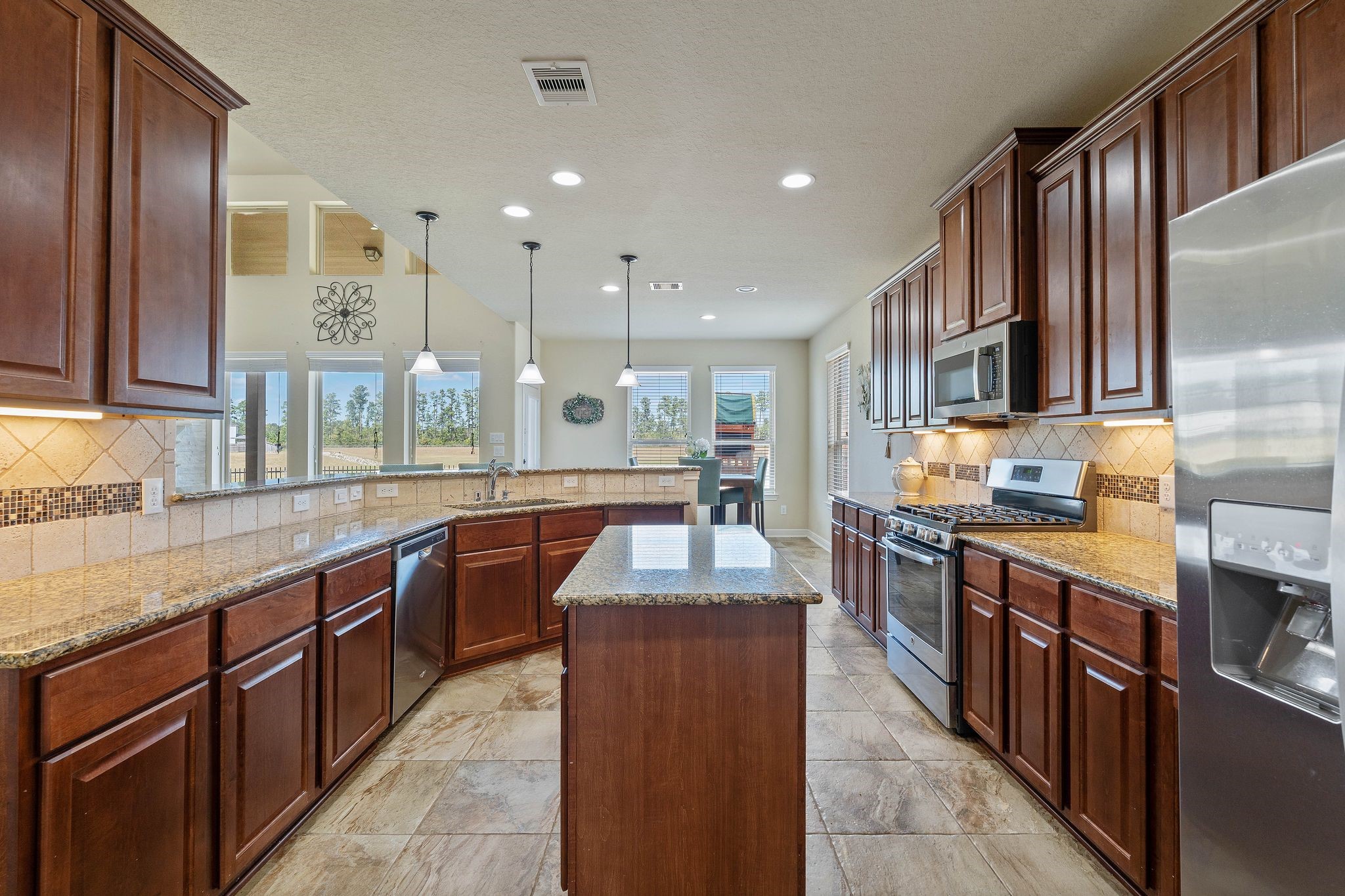 10114 North Whimbrel Circle Conroe, TX 77385 - Photo 16 of 50 a large kitchen with stainless steel appliances granite countertop a stove top oven a sink dishwasher a dining table and chairs with wooden floor