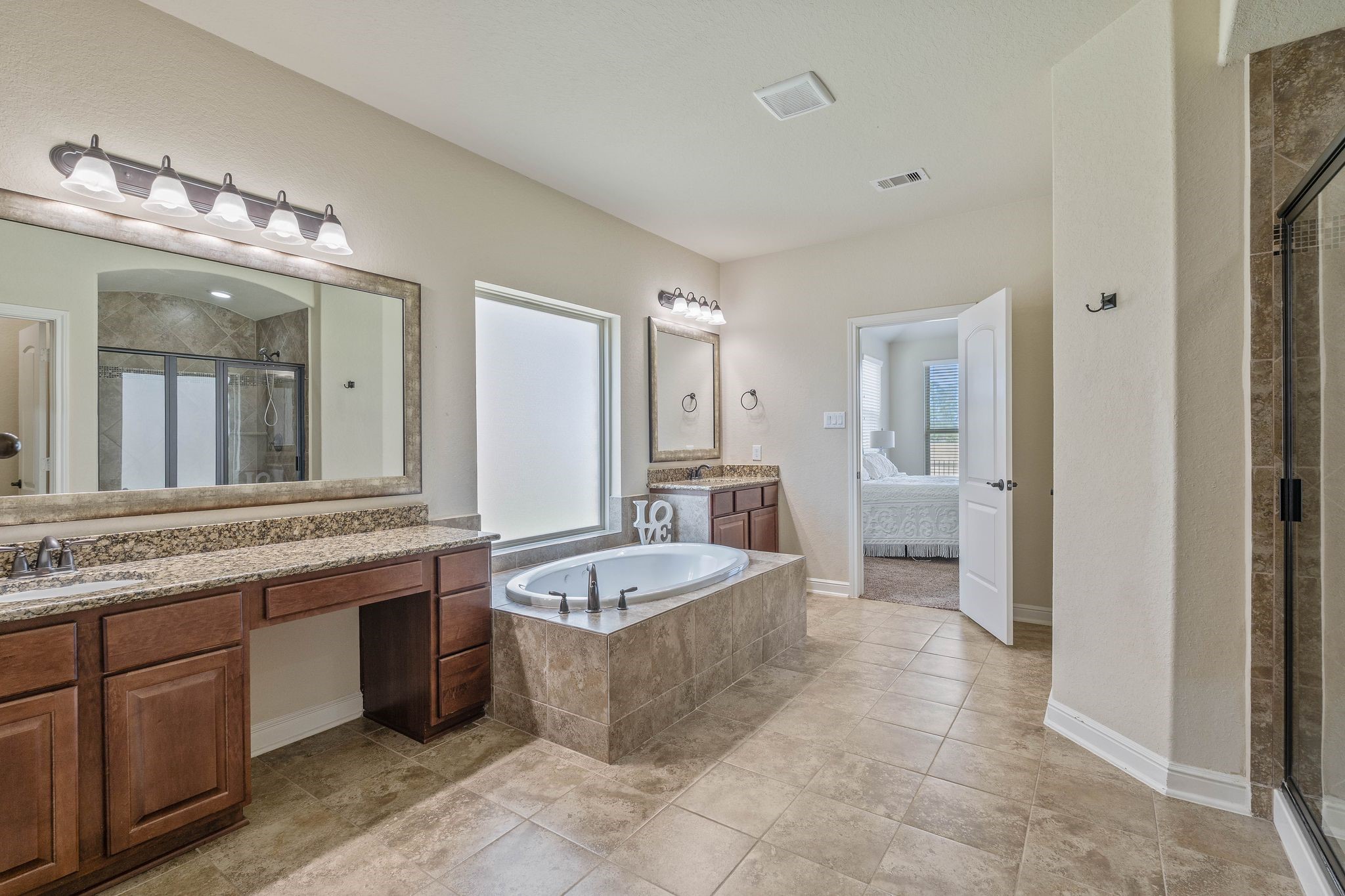 10114 North Whimbrel Circle Conroe, TX 77385 - Photo 26 of 50 a large bathroom with a granite countertop double vanity sink a mirror and a bathtub