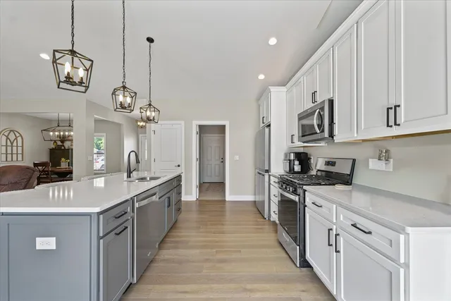 a large kitchen with stainless steel appliances granite countertop a sink a stove top oven a counter space and cabinets