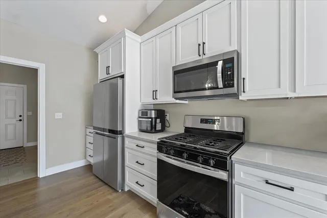 a kitchen with cabinets stainless steel appliances and wooden floor