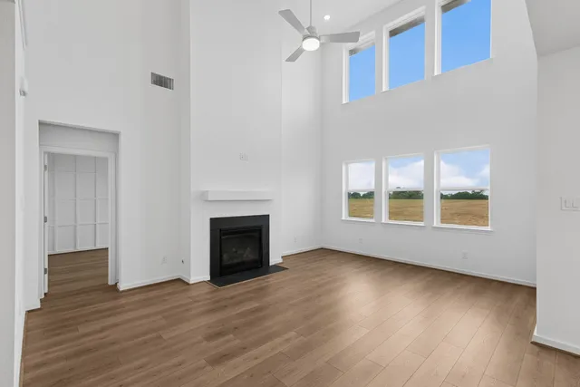 a view of an empty room with wooden floor fireplace and a window