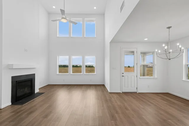 an empty room with wooden floor fireplace and windows