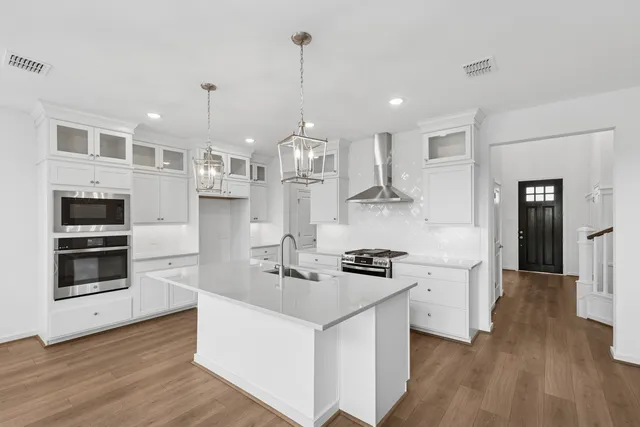 a kitchen with stainless steel appliances a stove top oven a sink dishwasher and a refrigerator with wooden floor