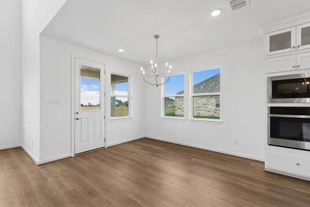 a view of an empty room with window and wooden floor