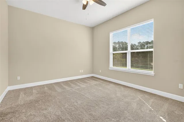 an empty room with a window and a fan