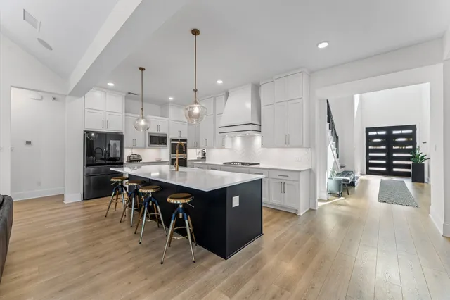 a kitchen with a table chairs wooden floors and a view of living room