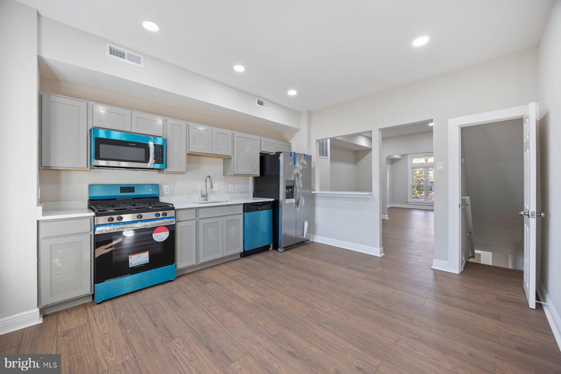 117 Collins Avenue Baltimore, MD 21229 - Photo 10 of 27 a kitchen with stainless steel appliances granite countertop a refrigerator a stove top oven a sink dishwasher and a refrigerator with wooden floor