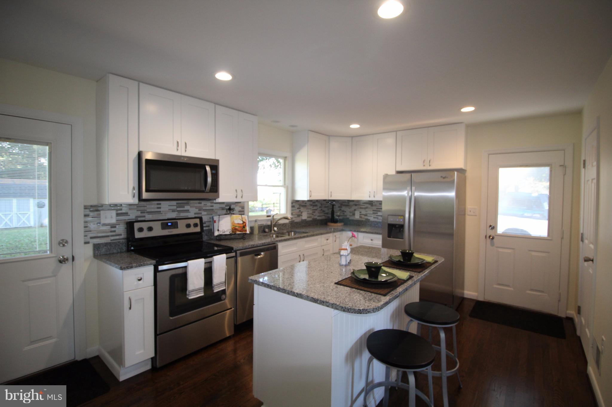 12805 Bunker Hill Road Union Bridge, MD 21791 - Photo 14 of 30 a kitchen with a refrigerator a stove a microwave oven with a dining table and chairs