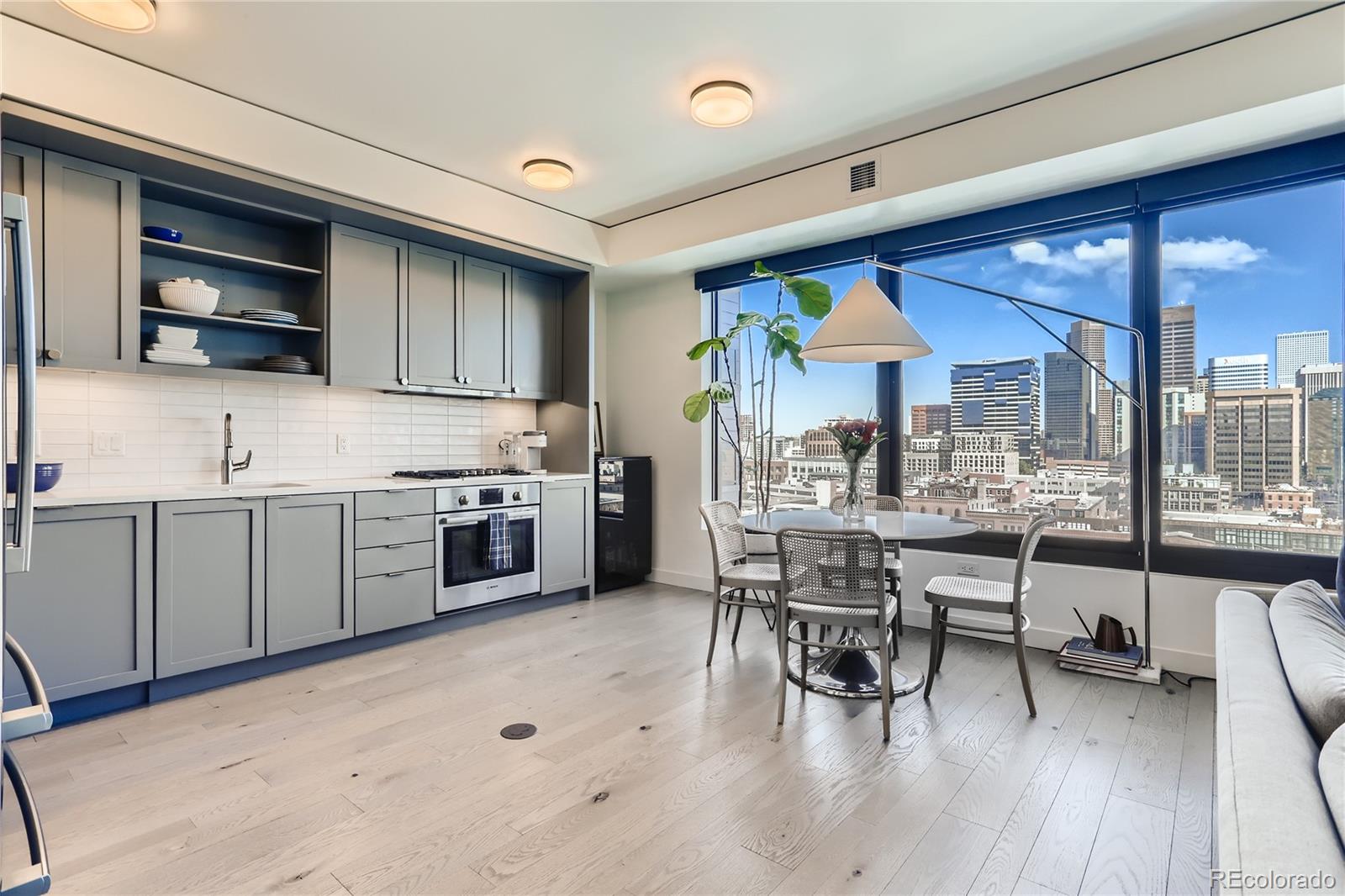 1750 Wewatta Street, Unit 1202 Denver, CO 80202 - Photo 3 of 16 a kitchen with stainless steel appliances granite countertop a stove top oven a sink dishwasher a dining table and chairs with wooden floor