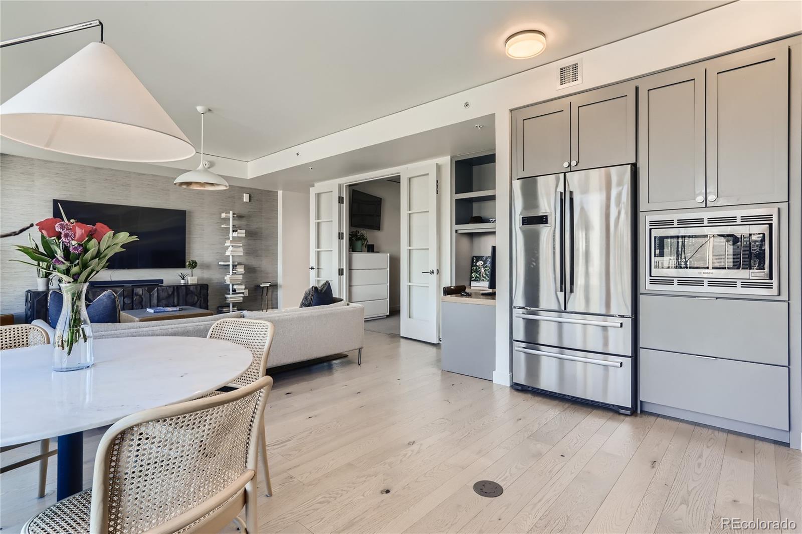 1750 Wewatta Street, Unit 1202 Denver, CO 80202 - Photo 4 of 16 a kitchen with stainless steel appliances a refrigerator a microwave a stove and white cabinets with wooden floor