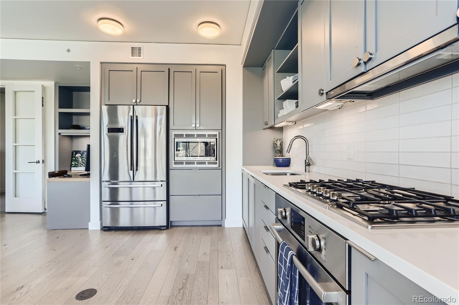 1750 Wewatta Street, Unit 1202 Denver, CO 80202 - Photo 5 of 16 a kitchen with stainless steel appliances a refrigerator a sink and white cabinets