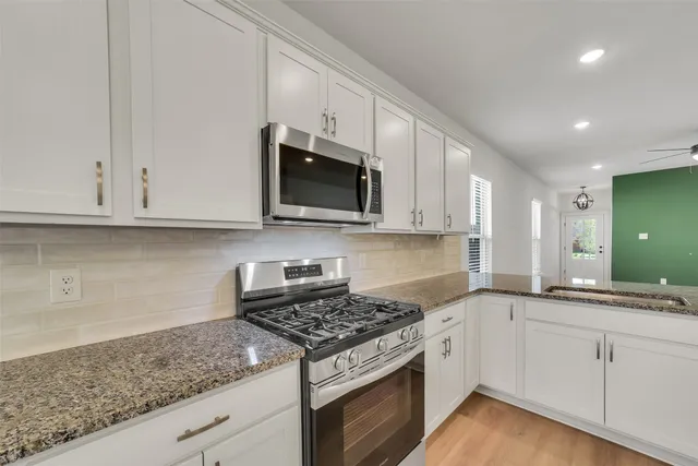 a kitchen with granite countertop white cabinets stainless steel appliances and a sink
