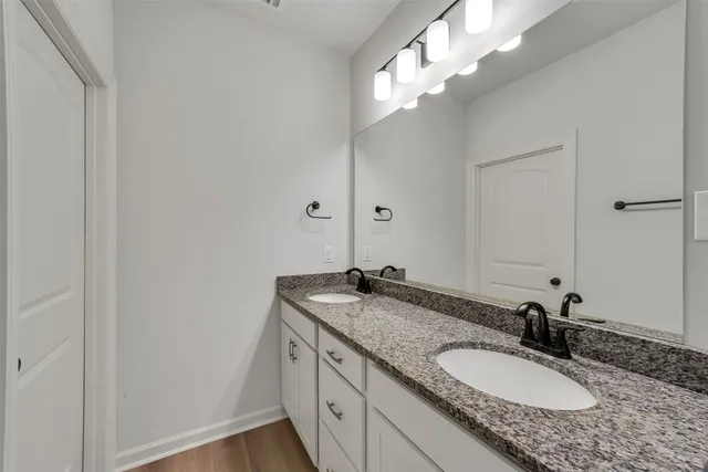 a bathroom with a granite countertop double vanity and a mirror