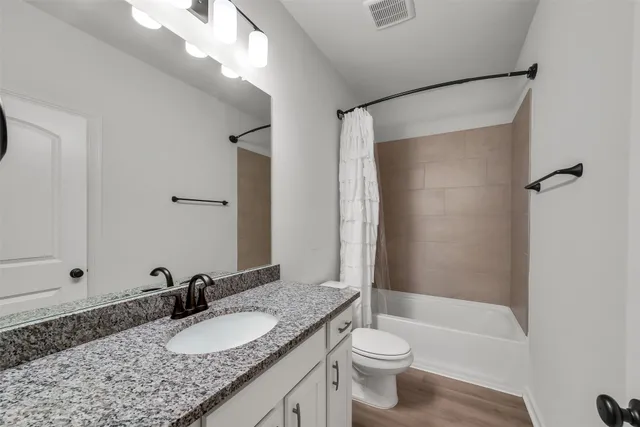 a bathroom with a granite countertop sink toilet and shower