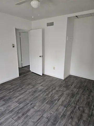a view of an empty room with wooden floor and closet