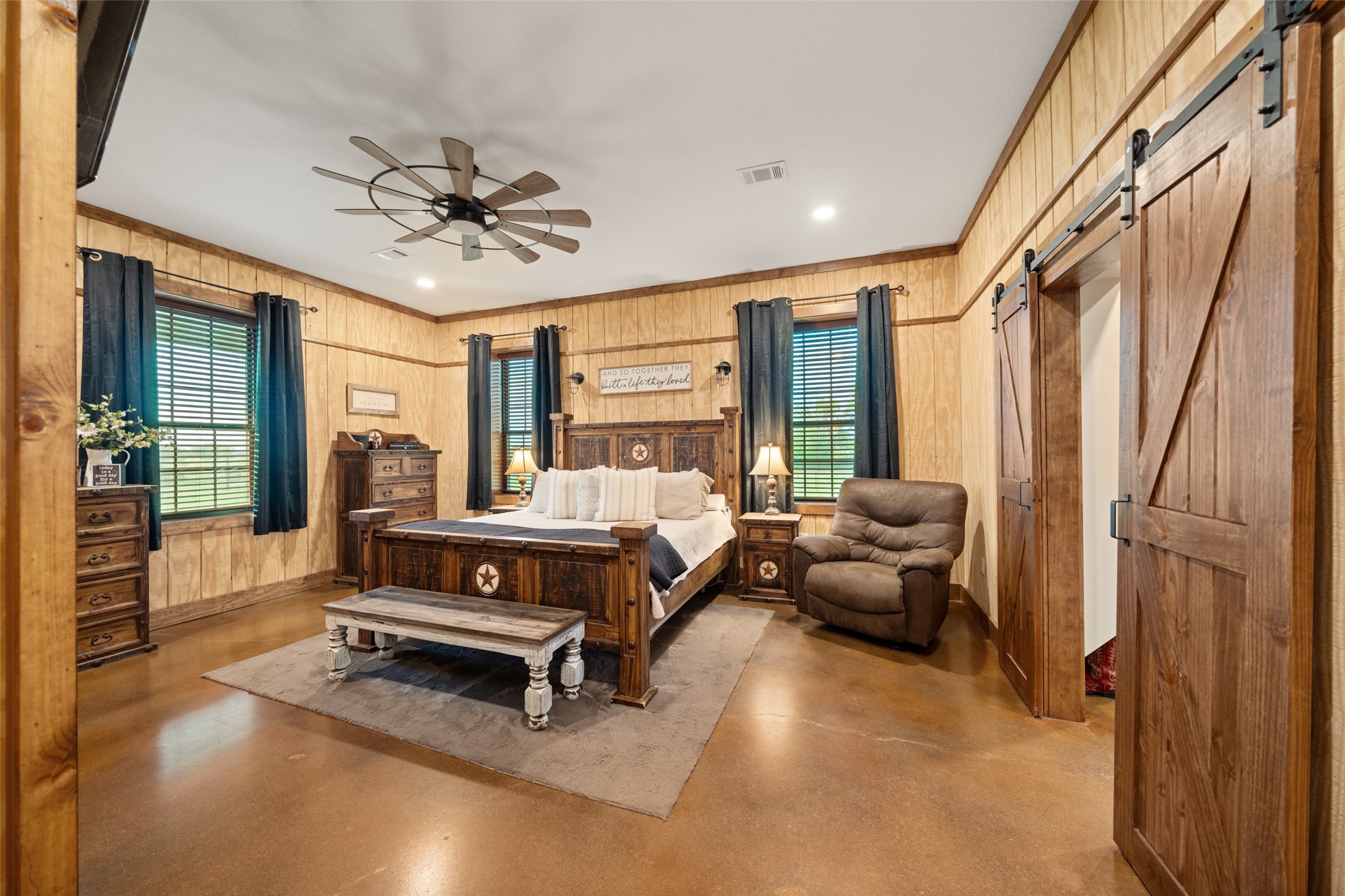 1402 Eagle Ferry Road Anahuac, TX 77514 - Photo 31 of 48 Polished concrete floors, expansive windows with solar screens, and multiple sightlines to the turnout pen create a serene retreat in this spacious primary suite enhanced by charming dual barn doors that open to the inviting en suite bath.