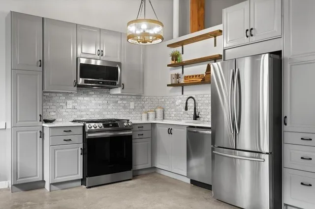 a kitchen with stainless steel appliances granite countertop a refrigerator a stove a microwave oven a sink with a refrigerator and cabinets