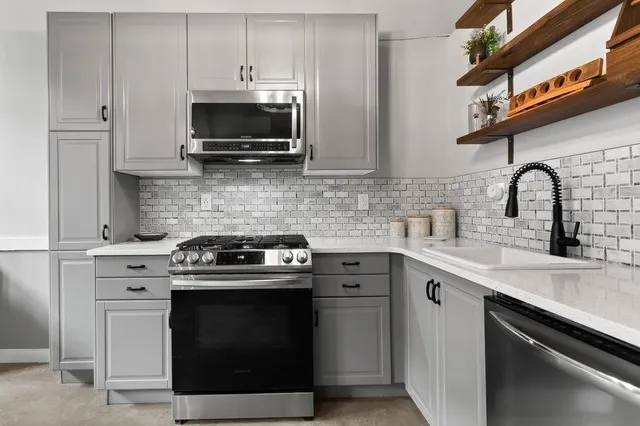 a kitchen with stainless steel appliances a stove a sink and a microwave