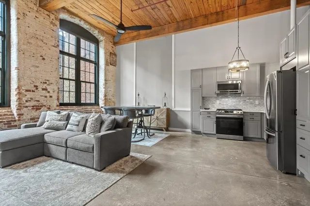 a living room with couches a flat screen tv and kitchen view