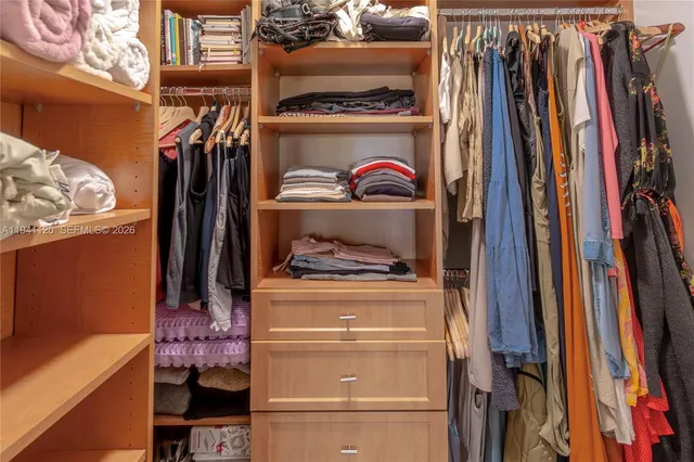 a view of walk in closet with clothes and shoes