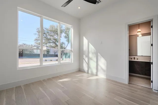 a view of an empty room with a window and wooden floor