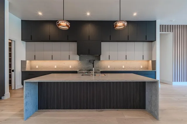 a kitchen with stainless steel appliances a sink a stove a refrigerator and a oven with wooden floor