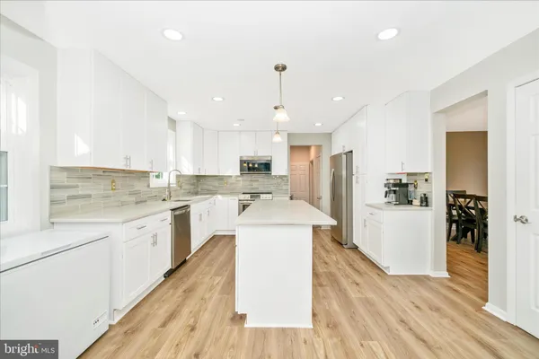 a large kitchen with kitchen island a sink a center island stainless steel appliances and cabinets