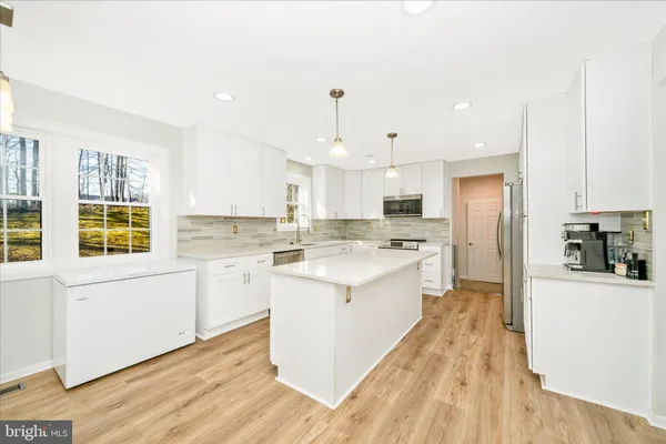 a large kitchen with stainless steel appliances kitchen island granite countertop a sink and cabinets