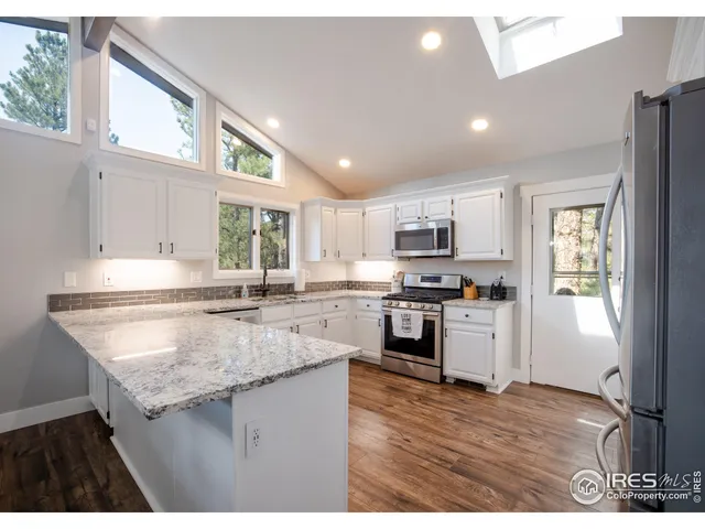 a kitchen with kitchen island granite countertop a stove top oven a sink dishwasher a dining table and chairs with wooden floor