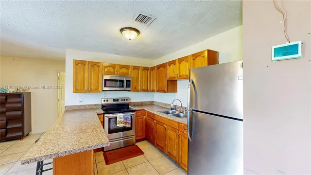 a kitchen with stainless steel appliances granite countertop a refrigerator a stove top oven a sink and dishwasher