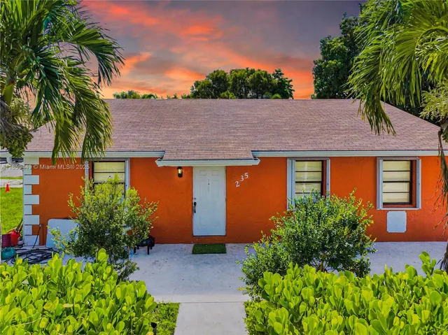 a backyard of a house with potted plants and palm trees