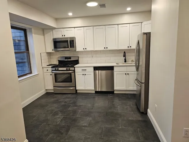 a kitchen with stainless steel appliances granite countertop a refrigerator a stove top oven a sink and dishwasher