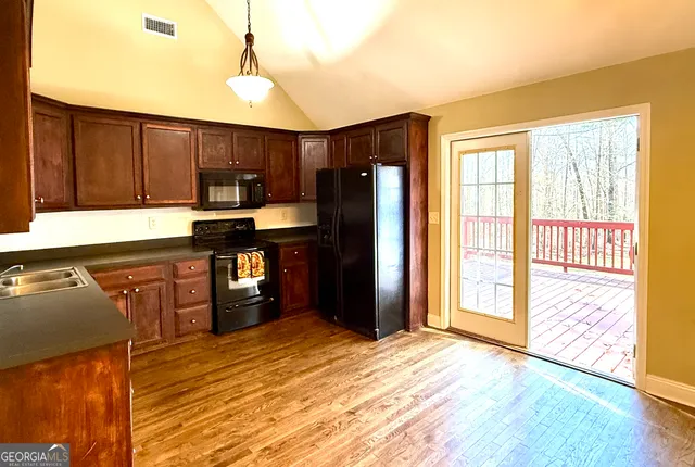 a kitchen with kitchen island granite countertop wooden cabinets a refrigerator and a sink