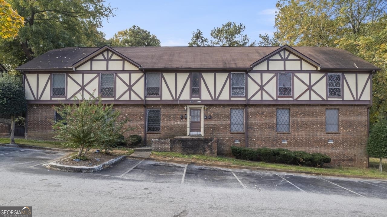 a view of a brick house with a yard and large trees