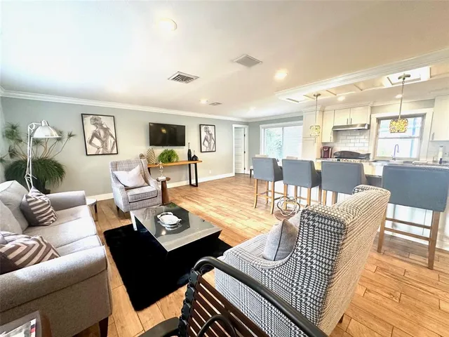 a living room with furniture couches and a dining table with wooden floor