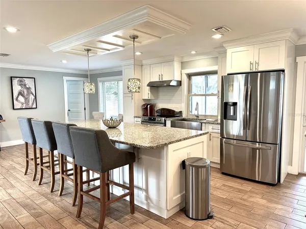 a kitchen with stainless steel appliances granite countertop a dining table chairs refrigerator and sink