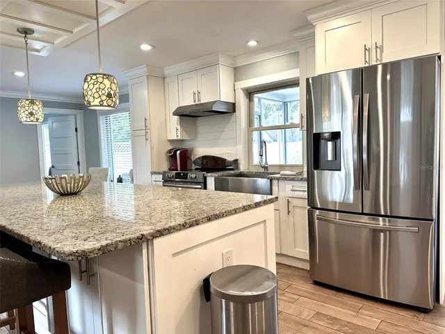 a kitchen with stainless steel appliances granite countertop a refrigerator a sink dishwasher a stove and a refrigerator