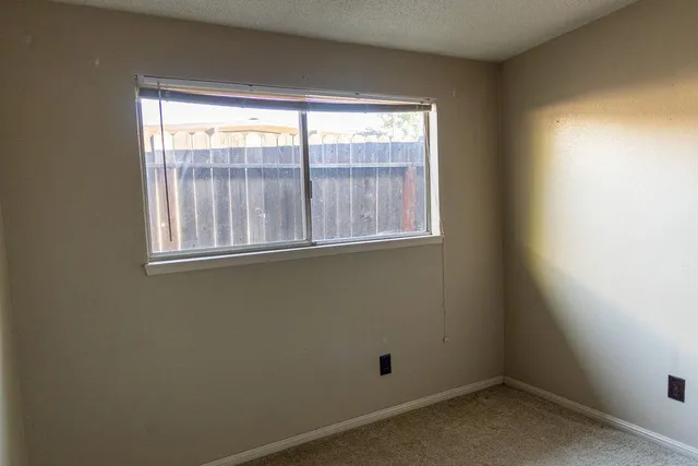 a view of a patio with table and chairs under an umbrella with a small yard