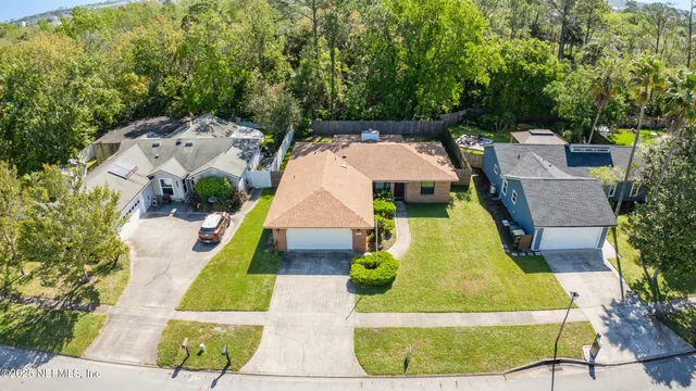 an aerial view of a house with swimming pool and large trees