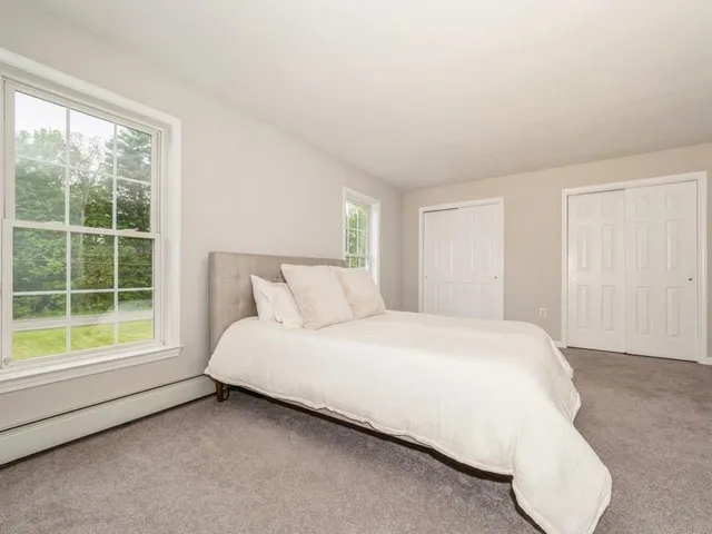 a large bed sitting in a bedroom next to a window