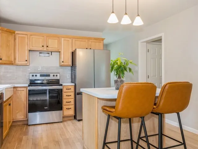 a kitchen with stainless steel appliances granite countertop a dining table chairs stove and refrigerator
