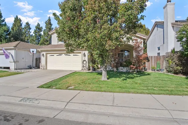 a front view of a house with a yard and trees