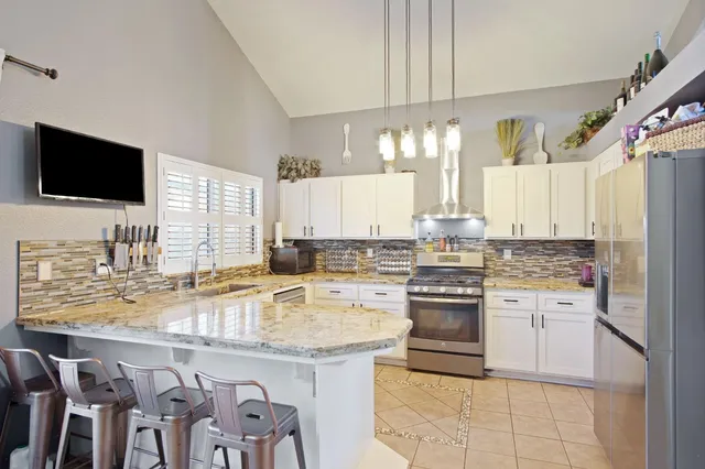 a kitchen with kitchen island granite countertop lots of white stainless steel appliances cabinets and a sink