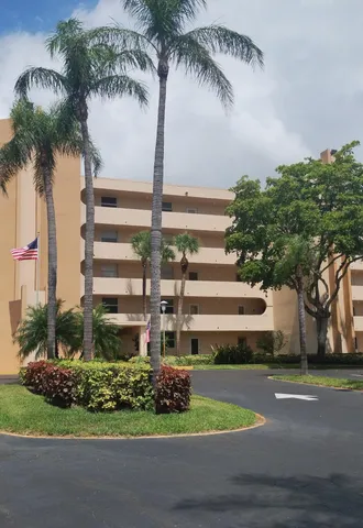 a front view of multi story residential apartment building with yard and sign board