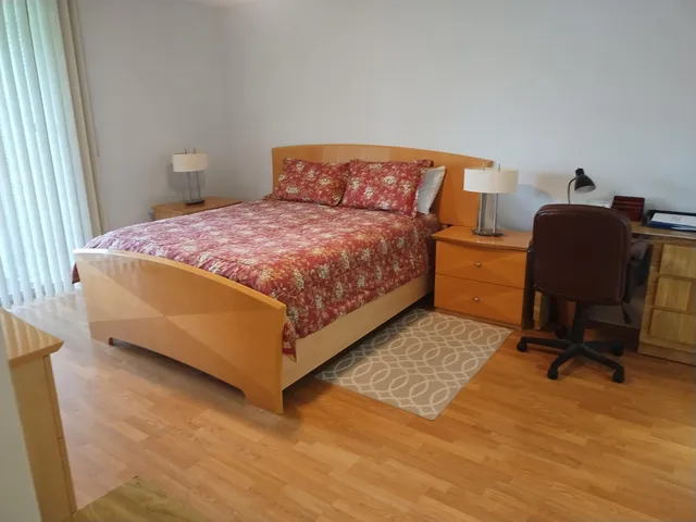 a bedroom with a bed a chair and a dresser next to a window