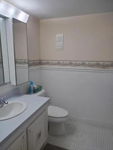 a bathroom with a granite countertop toilet sink and mirror