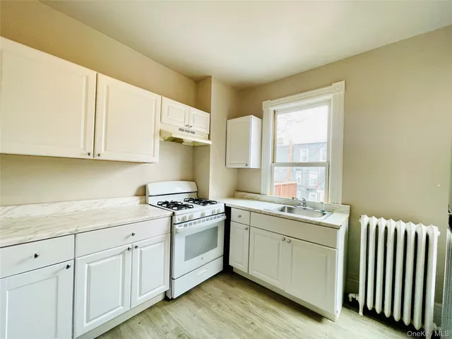a kitchen with a sink stove cabinets and wooden floor