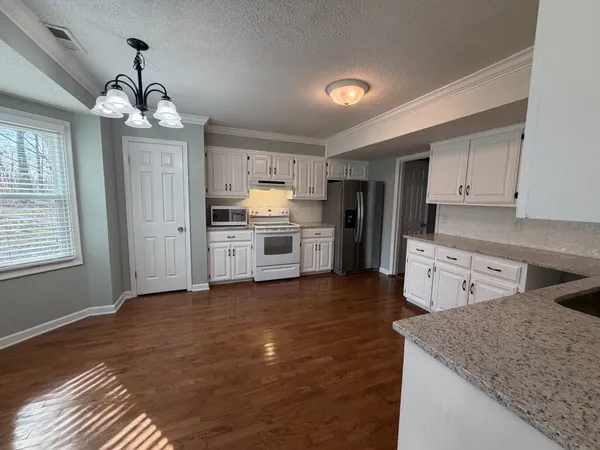 a kitchen with granite countertop white cabinets and a sink